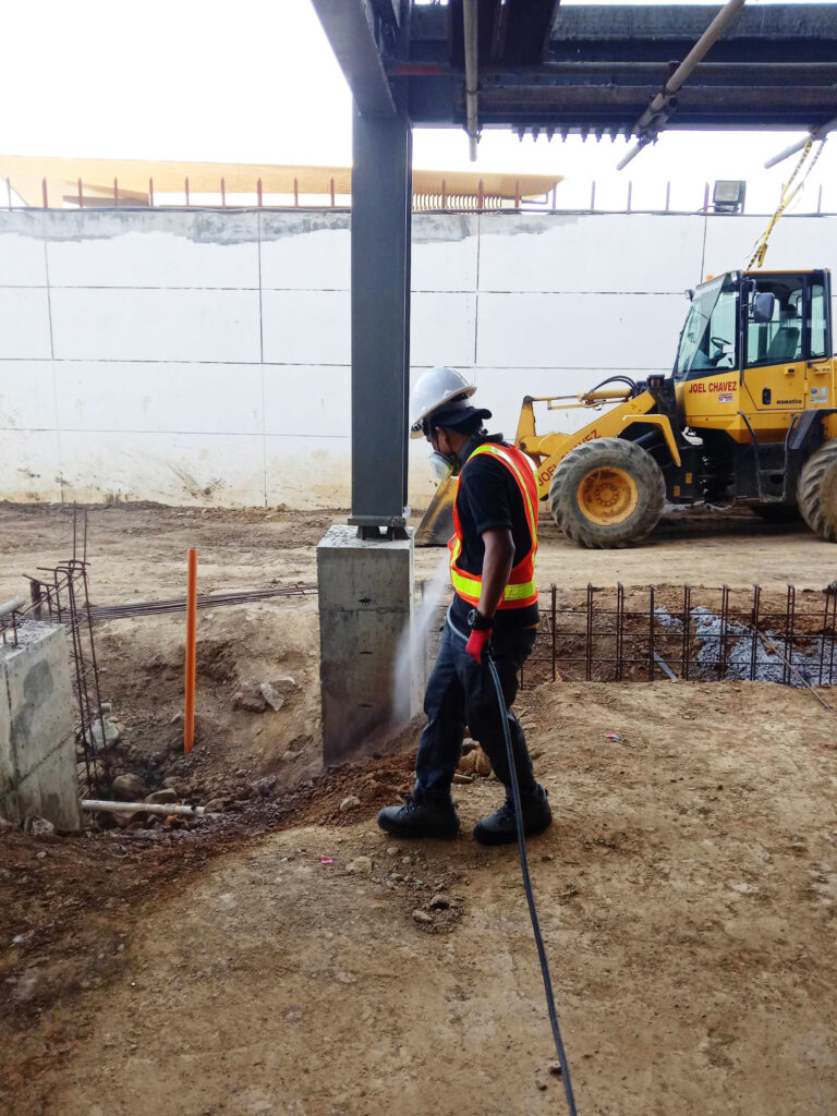 pest control professional soil treatment on one foundation of a warehouse under pre-construction
